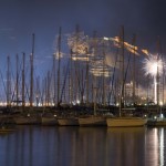 Los fuegos artificiales se reflejan en el puerto de la ciudad.